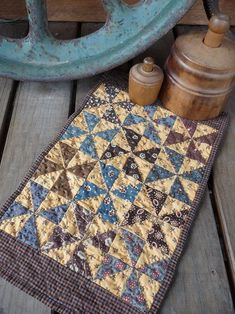 a quilted table runner sitting on top of a wooden floor next to a tea kettle