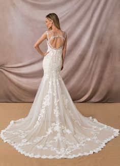 a woman in a white wedding dress standing against a backdrop