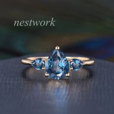 a ring with three pear shaped blue topaztes on it and the words network above it