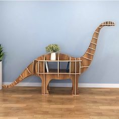 a wooden dinosaur shaped table with books on it's legs and a potted plant in the middle