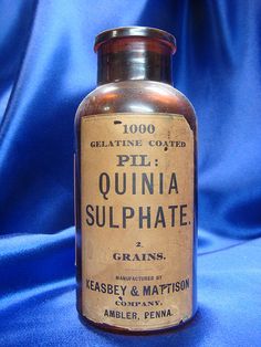 an old bottle of quinia sulphate sitting on a blue cloth covered table