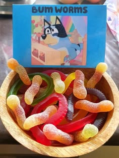 a bowl filled with gummy bears sitting on top of a table next to a book