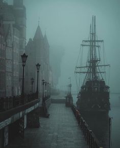 a boat is docked in the water near some buildings on a foggy day,