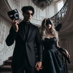 a man and woman dressed in black standing next to each other with masks on their faces