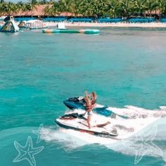 a person on a jet ski in the water with palm trees and blue skies behind them