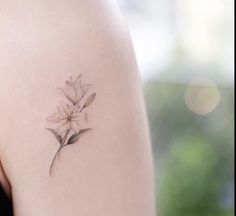 a woman's arm with a flower tattoo on the left side of her shoulder