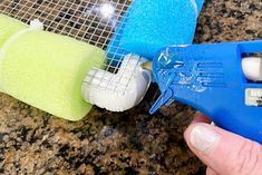 a hand holding a blue and white plastic blow dryer next to two sponges