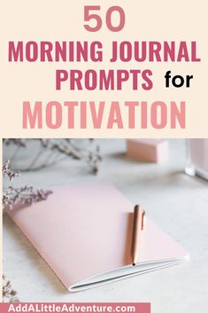 a pink notebook sitting on top of a white table next to a cup and plant