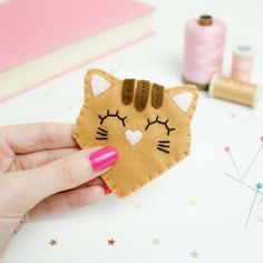 a hand holding a piece of felt with a cat face on it