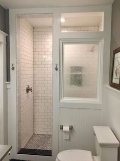 a bathroom with a white toilet sitting next to a walk in shower and a window