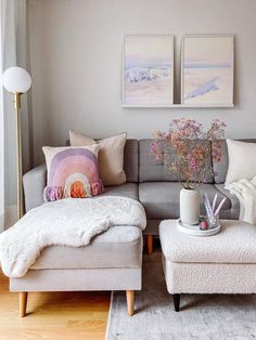 a living room with a couch, ottoman and two pictures on the wall above it