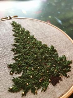 a close up of a cross stitch christmas tree ornament on a piece of cloth