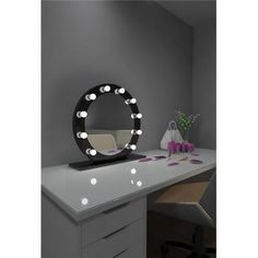 a desk with a mirror and some lights on it in front of a gray wall