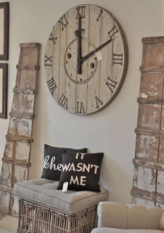 a large clock mounted to the side of a wall next to a wicker chair