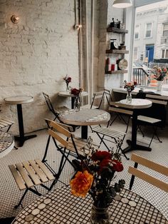 the interior of a restaurant with tables and chairs, flowers in a vase on the table