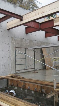 an unfinished room with concrete walls and wooden beams