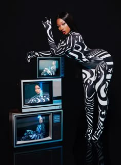 a woman standing on top of three televisions in front of a black background with zebra print