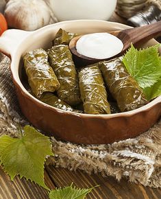 a bowl filled with stuffed grape leaves next to some vegetables