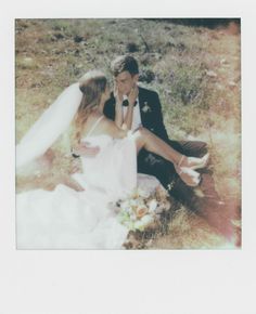 a bride and groom sitting on the ground