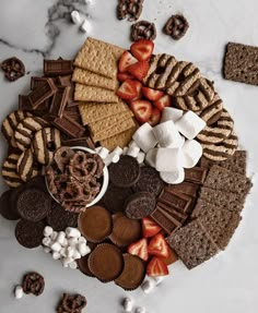 a platter filled with crackers, strawberries, chocolate and marshmallows