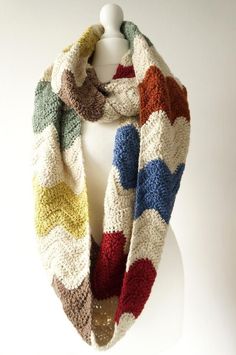 a multicolored knitted scarf hanging on a mannequin