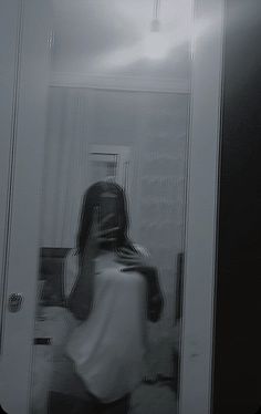 a woman standing in front of a mirror with her back turned to the camera,