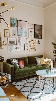 a living room with green couches and pictures on the wall above them, along with other furniture