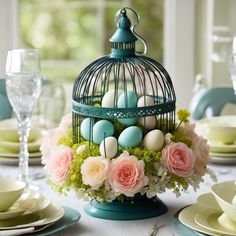 a birdcage filled with eggs sitting on top of a table next to plates