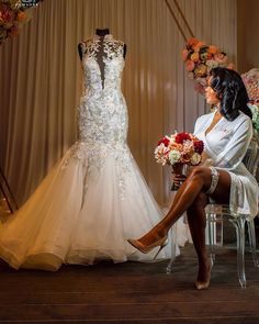 a woman sitting on a chair in front of a wedding dress and flower bouquets