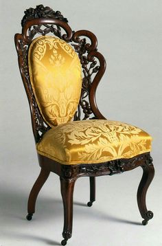 an ornately carved chair with yellow upholstered seat