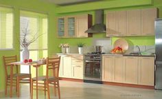 the kitchen is painted bright green and has wooden chairs at the table with fruit on it