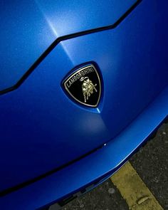 the front end of a blue car with a horse emblem on it's side