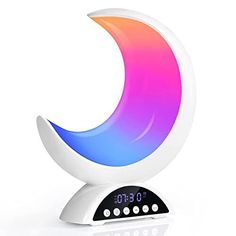 an alarm clock sitting on top of a white surface with a rainbow moon in the center