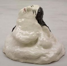 a white and black figurine sitting on top of a rock