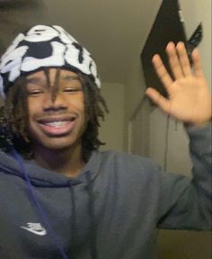 a man with dreadlocks and a hat holding his hands up in the air