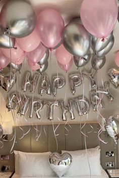 a bed topped with lots of pink and silver balloons