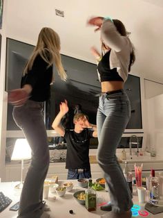 two women and a man are dancing in the kitchen