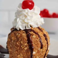 an ice cream sundae on a white plate with chocolate sauce and cherries in the background