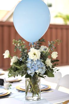 a vase filled with blue and white flowers sitting on top of a table next to a balloon