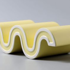 two yellow and white plastic objects on a gray surface, one is shaped like a wave