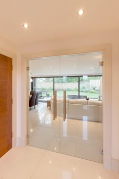 an open door leading to a living room with white tile flooring and large sliding glass doors