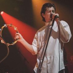 a man standing in front of a microphone on top of a stage holding a hoop