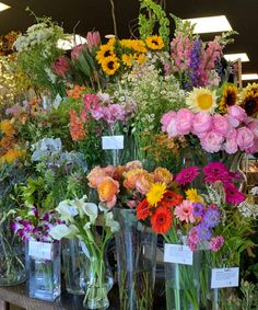 many different types of flowers in vases on display at a flower shop with price tags