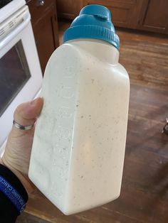 a person holding up a bottle with something in it on the kitchen counter next to an oven