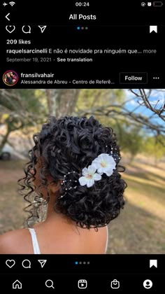 the back of a woman's head with curly hair and flowers in her hair