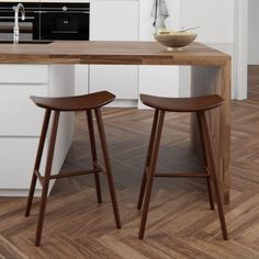 two wooden stools sitting in front of a kitchen counter with a bowl on it