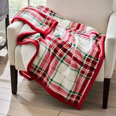 a red and green plaid blanket sitting on top of a chair next to a window