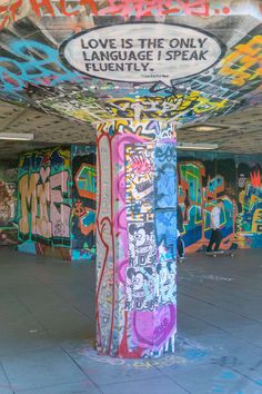 graffiti is painted on the walls and pillars in an area with concrete floors, which has been used as a shelter for children to play