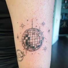 a person with a tattoo on their leg that has a disco ball and stars around it