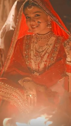 a woman dressed in red and gold sitting down